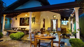 A covered outdoor seating area with tables and chairs, a hanging light fixture, and potted plants. - Conch Villa (Tangalle)