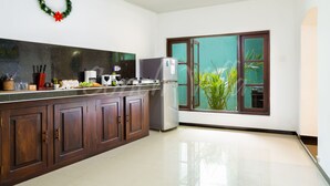 A modern kitchen with dark wooden cabinets, a stainless steel refrigerator, and a large window with a view of greenery. - Conch Villa (Tangalle)