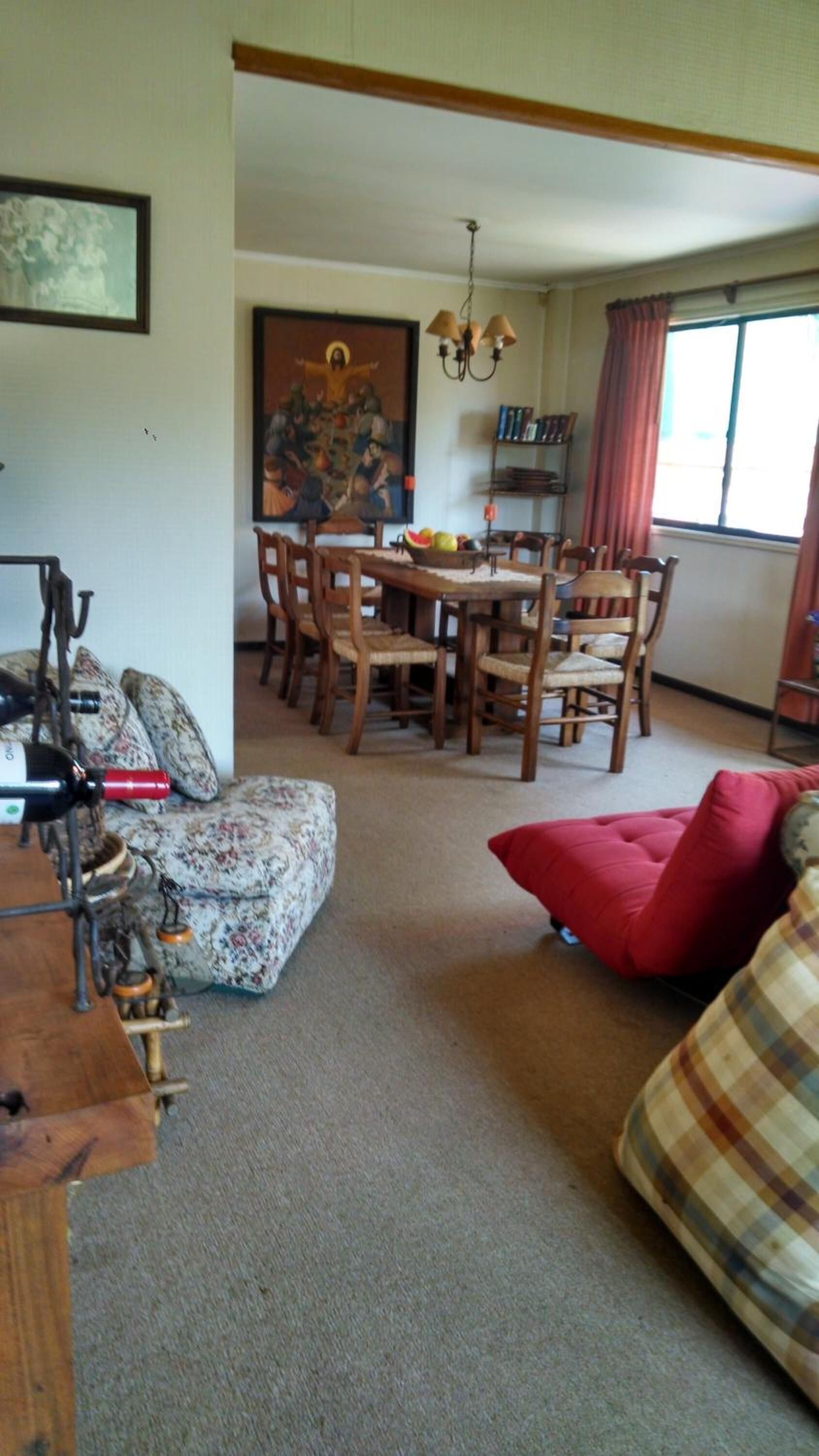A living room with a dining area, a red sofa, a wooden table, and a chandelier.