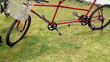 A red bicycle with a basket and pedals, parked on grass.
