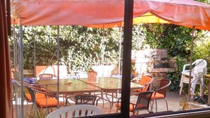 A view from inside a room with a large window overlooking an outdoor patio area with tables and chairs, and a wooden deck. - B&B Rocas Santo Domingo (Santo Domingo)