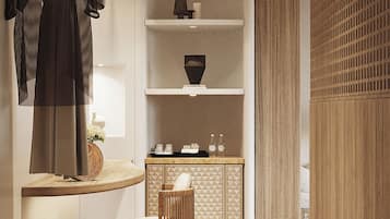 Un interior moderno con piso de madera, un perchero, una repisa con adornos y un mueble con respaldo tejido.