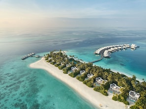 An aerial view of a resort with overwater bungalows, a sandy beach, and clear turquoise waters. - Jumeirah Olhahali Island  (Olhahali)