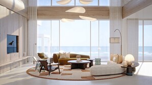 Un salon moderne doté d’une grande fenêtre donnant sur l’océan, d’un canapé, de fauteuils, d’une table basse et d’un lampadaire.