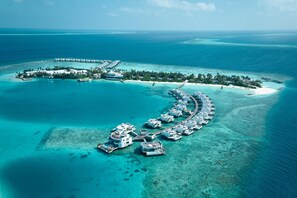 An aerial view of a resort island with overwater bungalows connected by a dock. - Jumeirah Olhahali Island  (Olhahali)