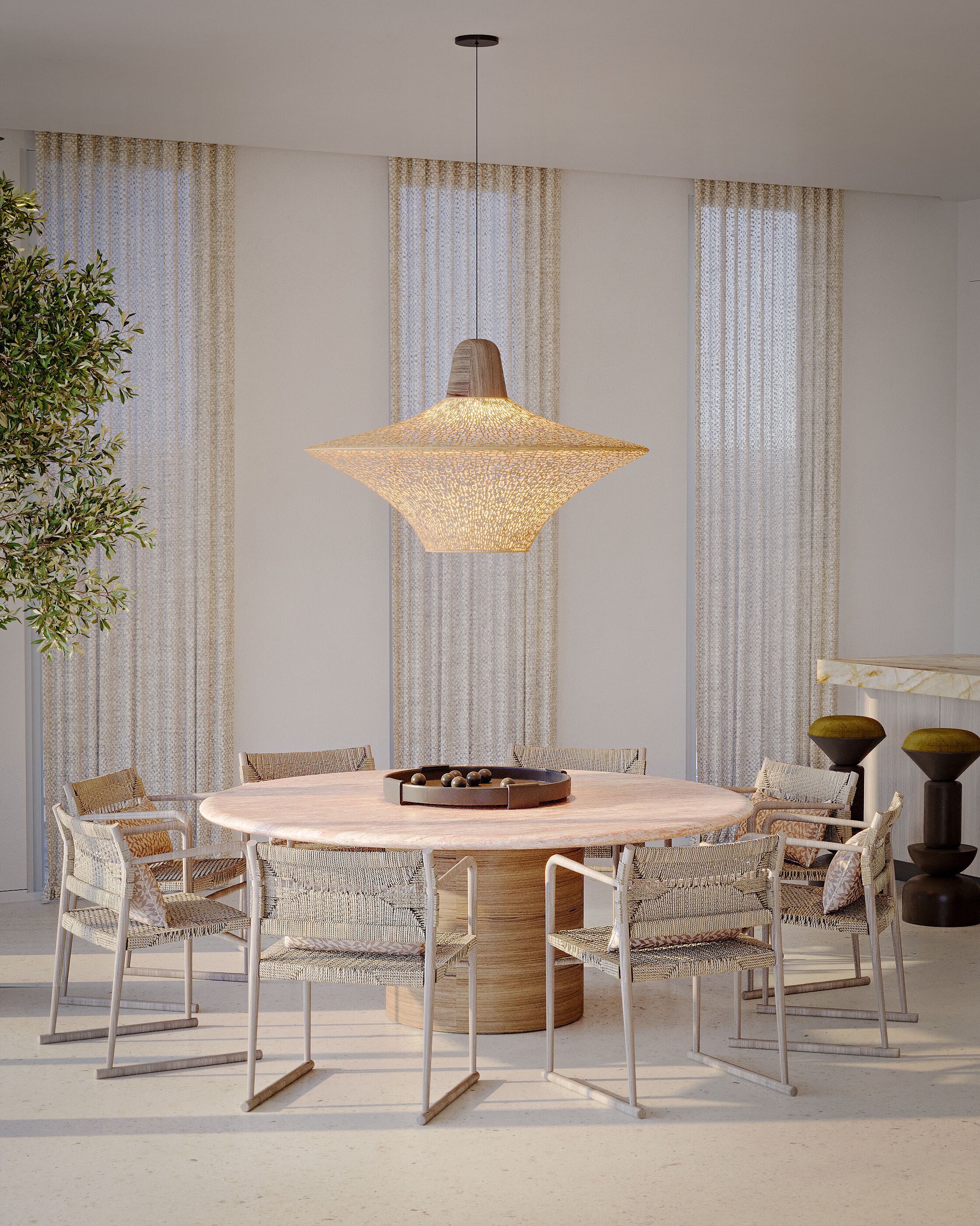 Un comedor con una mesa redonda, sillas de mimbre, una lámpara colgante y cortinas.