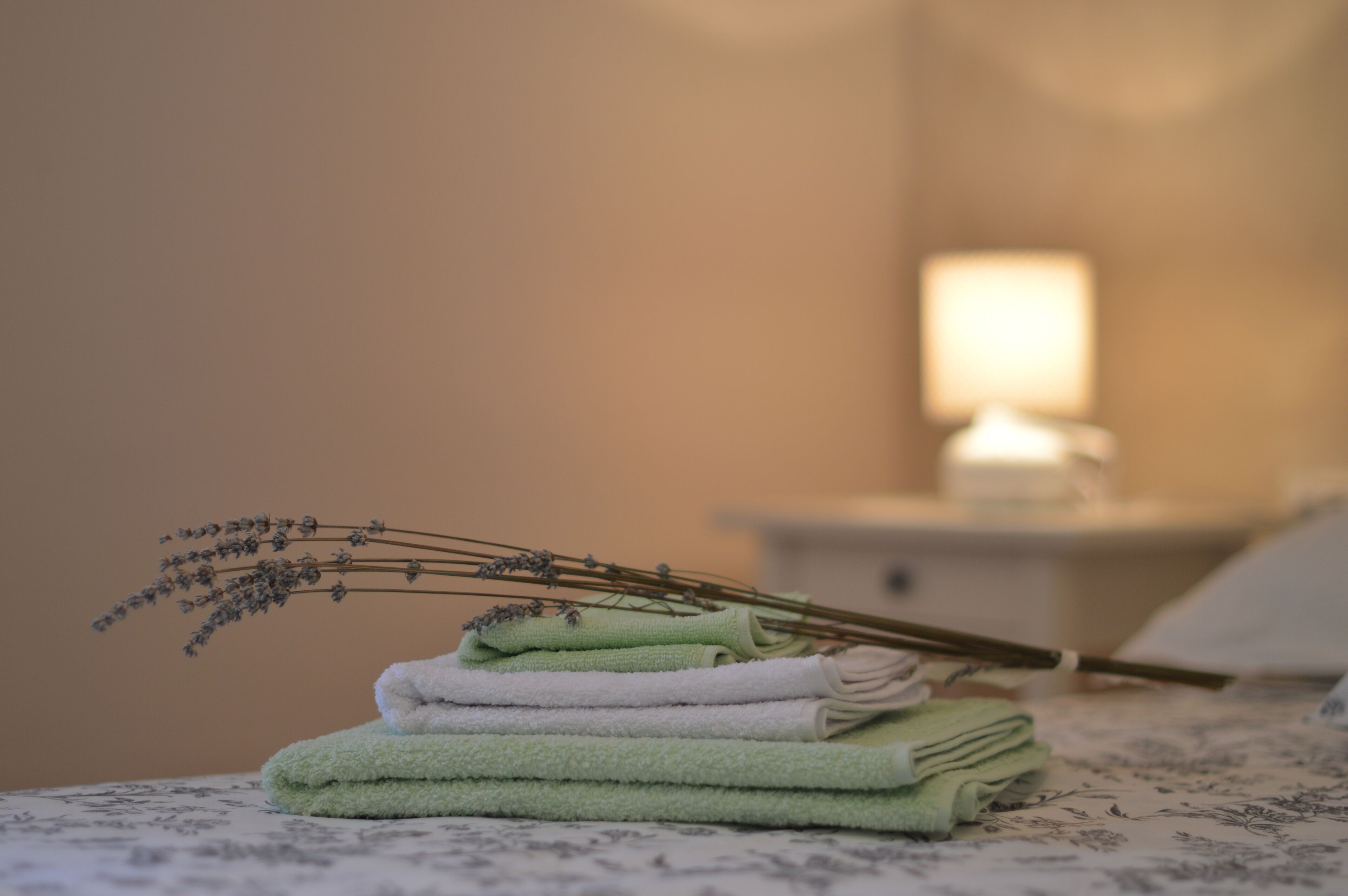 A neatly folded stack of towels on a bed with a floral-patterned bedspread.