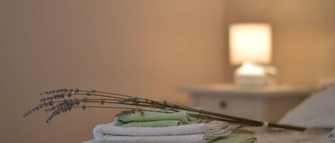A neatly folded stack of towels on a bed with a floral-patterned bedspread.