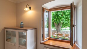 Une pièce dotée d’une banquette intégrée près d’une fenêtre, donnant sur un jardin avec un arbre et des meubles d’extérieur.