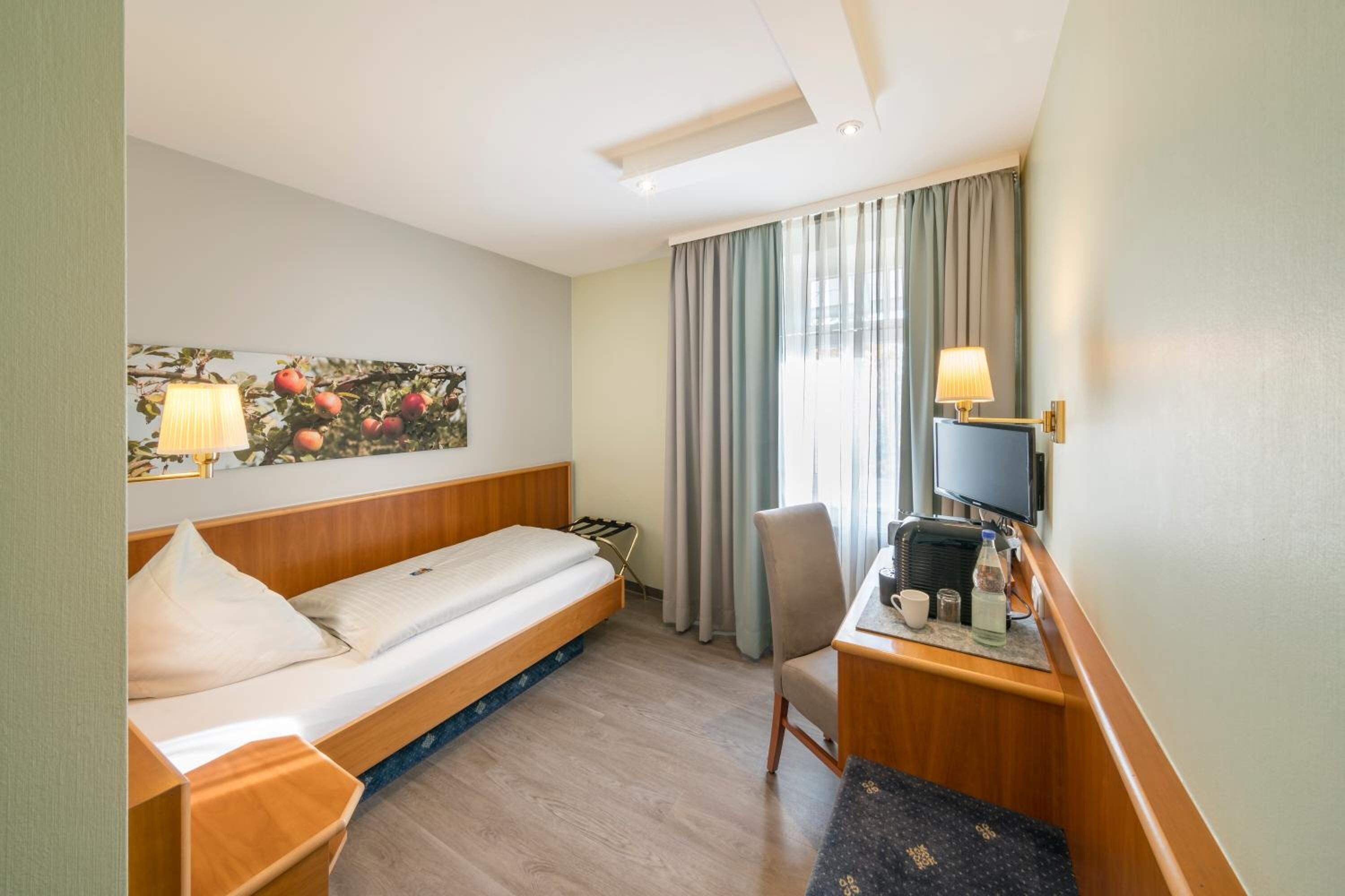 Habitación de hotel con cama, escritorio, silla y televisor.