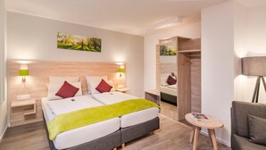 Une chambre d’hôtel moderne avec un grand lit, des lampes de chevet, une petite table et un canapé.