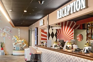 Un espace d'accueil comprenant un comptoir, une enseigne de bar, un mur décoratif et un miroir.