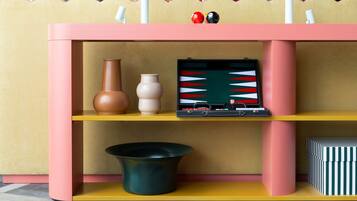 A pink and yellow shelf unit with decorative items including vases, a bowl, and a framed picture.