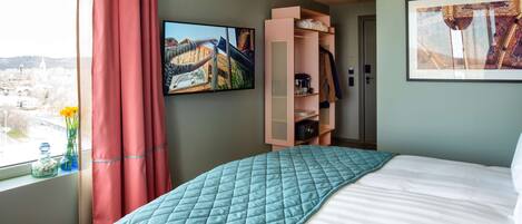 Un dormitorio con cama, ventana con vista a la ciudad, un armario rosa y un cuadro en la pared.