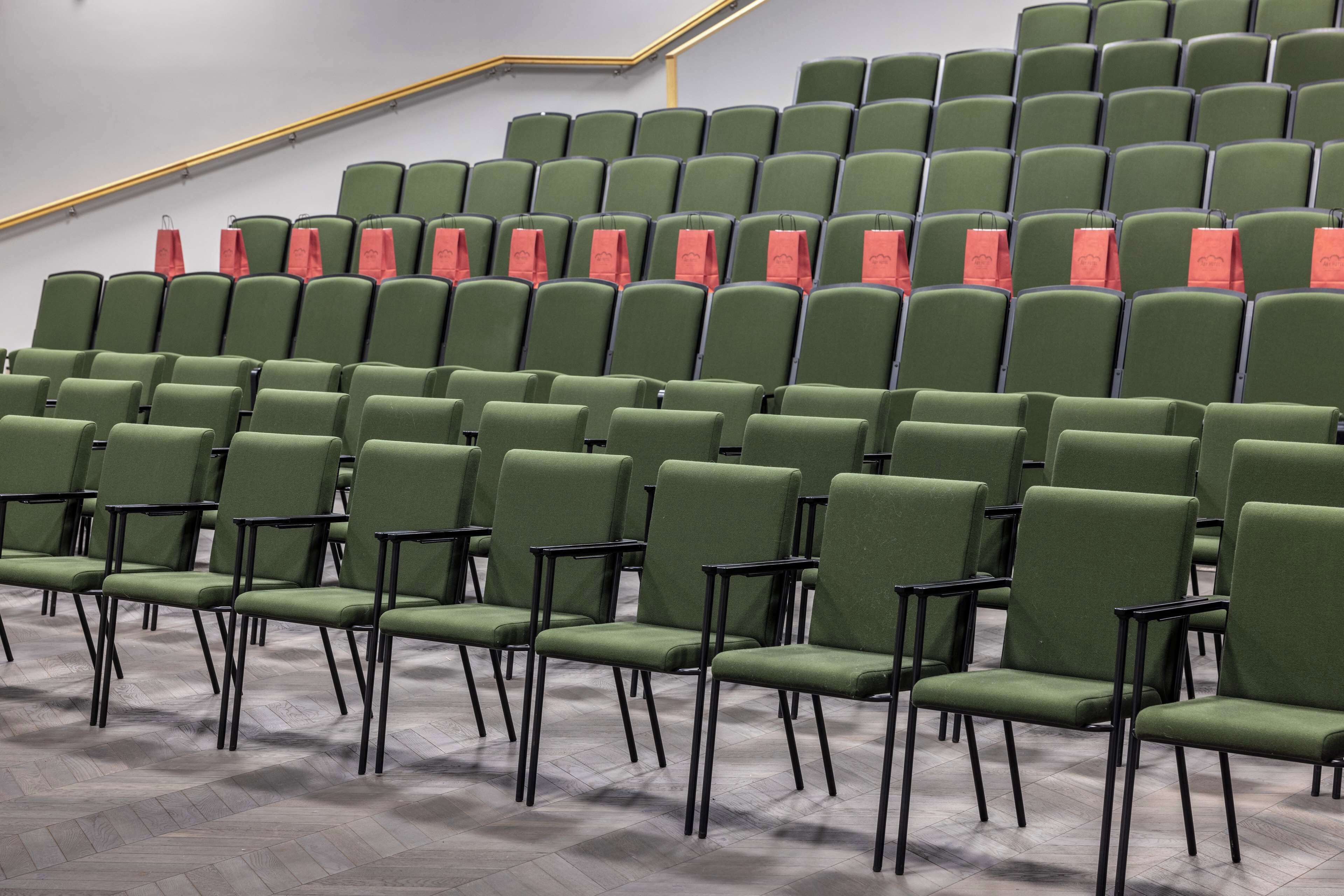 Rows of green chairs with black frames in a seating area.
