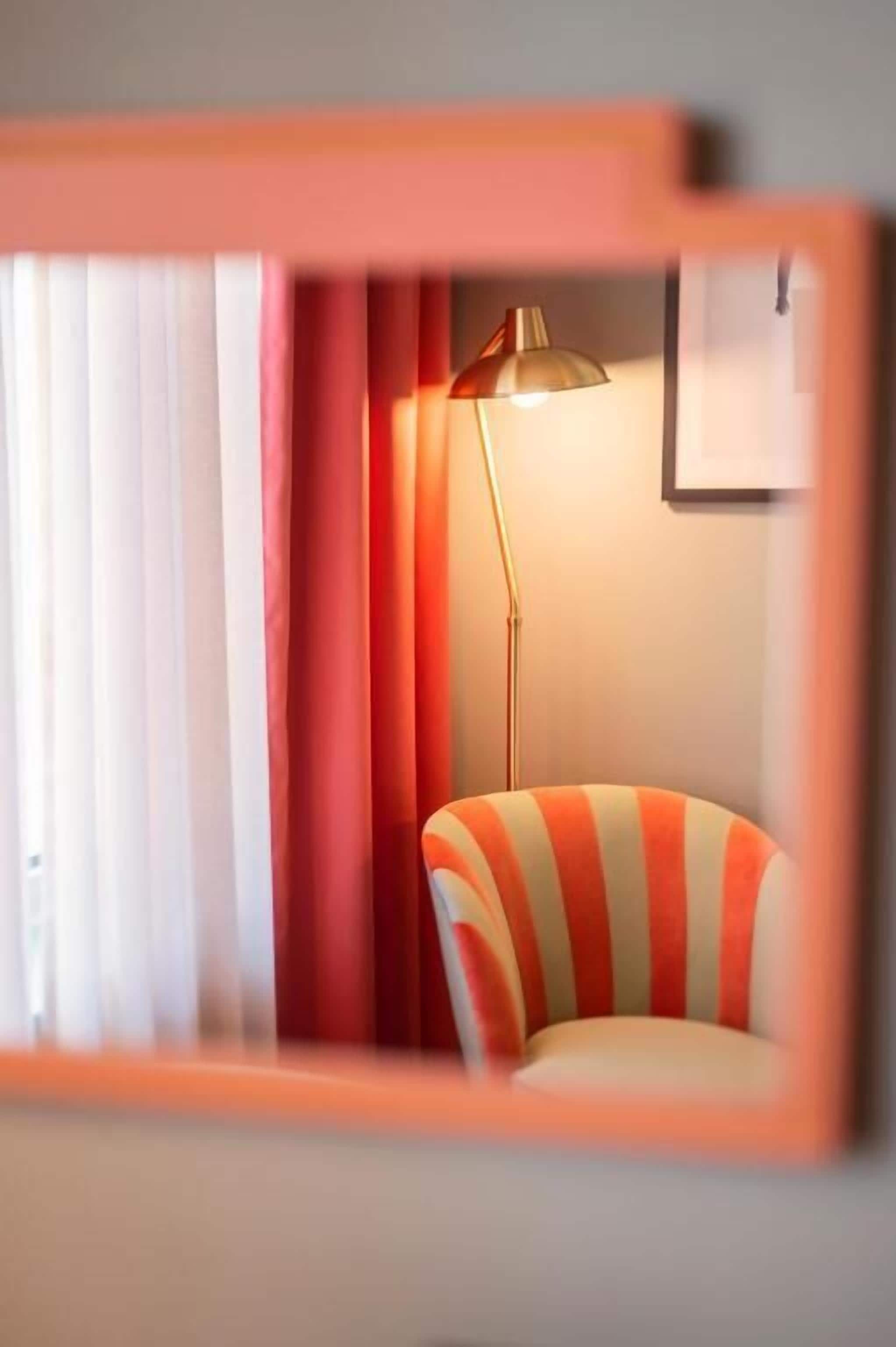 A room with a striped armchair, a floor lamp, and a window with curtains.