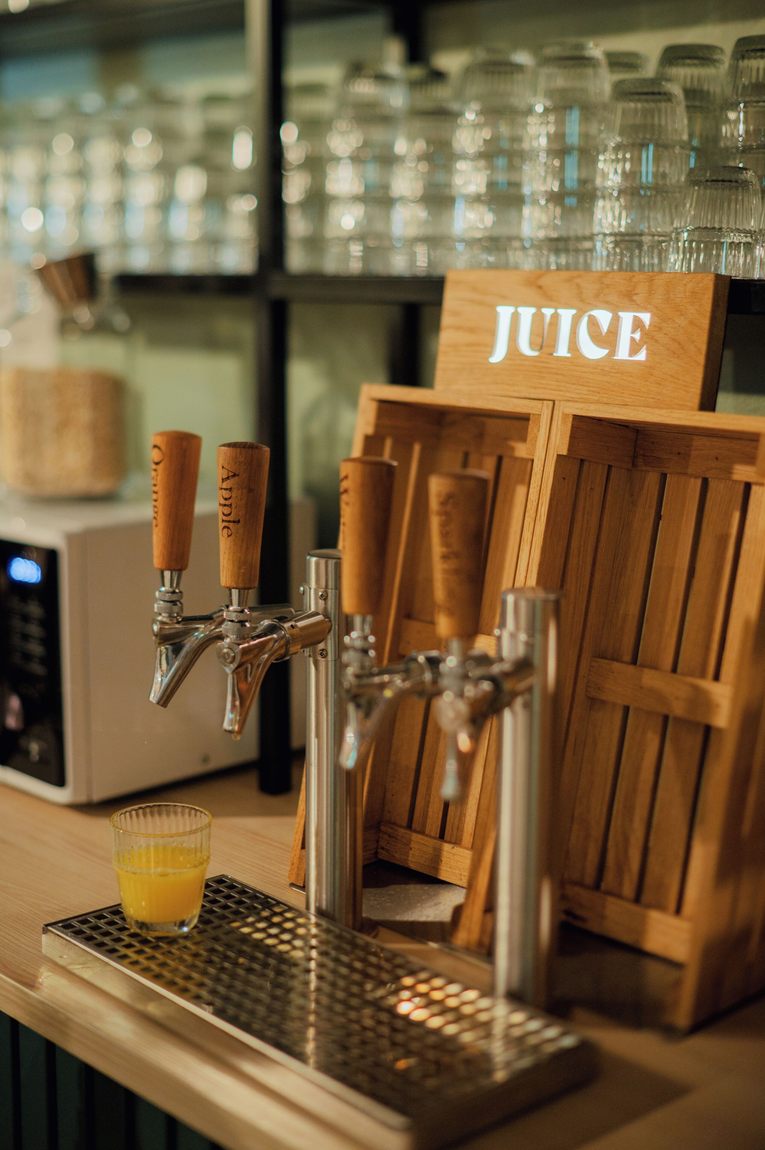 Una llave dispensadora de zumo con pomos de madera y un letrero que dice "JUICE" encima.
