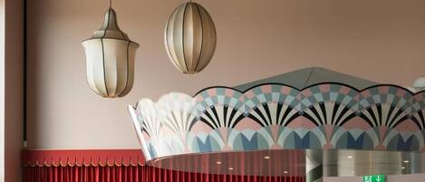 L’intérieur d’un restaurant, avec des suspensions décoratives, un plafond orné de motifs et un rideau rouge.