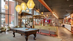 Een pooltafel in een helder verlichte ruimte met grote ramen, een draaimolen en een receptie.