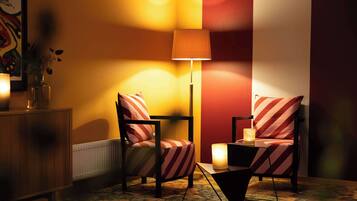 A room with two striped armchairs, a floor lamp, and a table with candles.