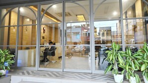 A modern building with large glass windows, interior seating, and potted plants. - Hotel Simran (Raipur)
