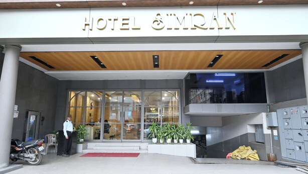 The entrance of Hotel SMIRAN with a modern facade, large glass doors, and a security guard standing outside. - Hotel Simran (Raipur)