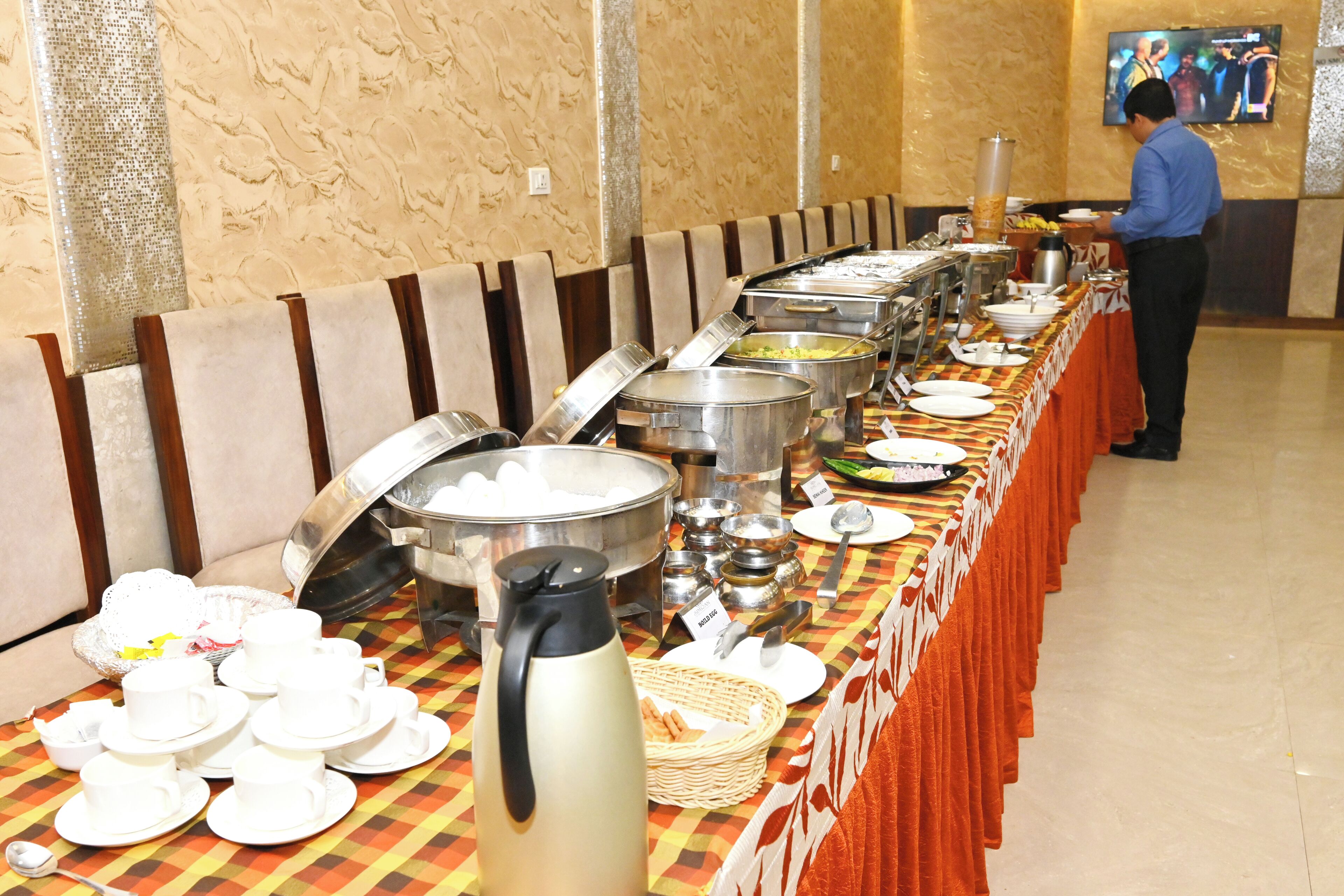 A buffet setup with various food containers and utensils on a checkered tablecloth.
