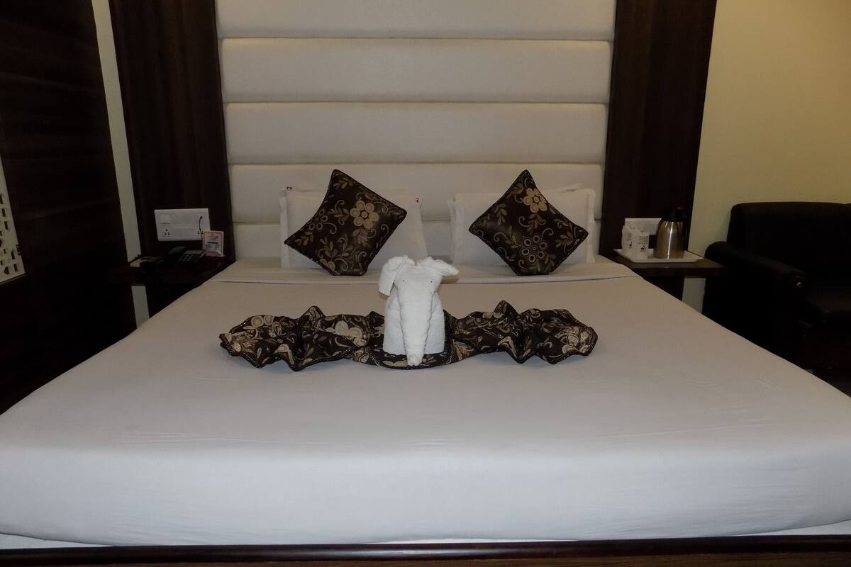 A neatly made bed with a towel and a decorative pillow, a bedside table with a lamp, and a chair.