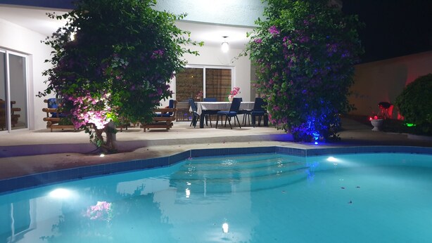 A swimming pool with a patio area, surrounded by lush greenery and a table with chairs. - Superb villa with pool, 5 minutes from Saly (Ngaparou)