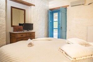 Une chambre à coucher avec un grand lit, une commode, un téléviseur et une fenêtre avec une porte bleue.