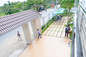 A hotel courtyard with tiled flooring, a blue awning, and a sign for the hotel. - Hung Long Hotel (Luong Hoa)