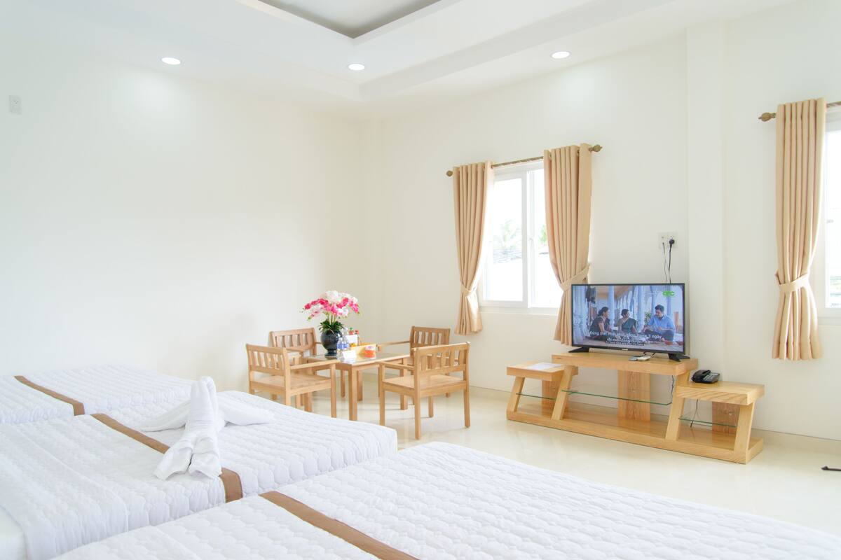 A hotel room with two beds, a TV, a desk, and a chair.
