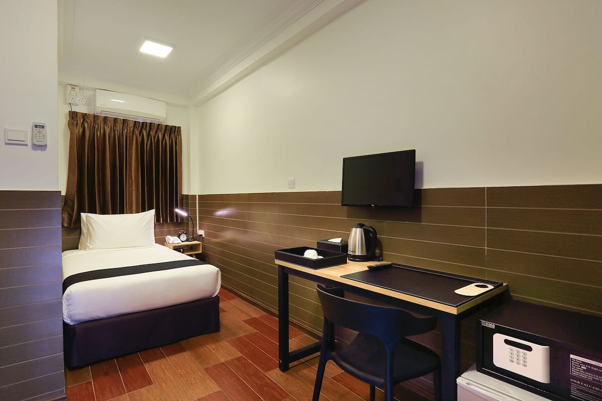 Quarto de hotel com cama, escrivaninha, cadeira, televisão e cafeteira.
