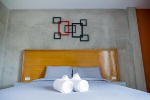 A hotel room with a wooden headboard, a bed with white linens, and a wall art piece above the bed. - B3 Hotel (Nakhon Si Thammarat)