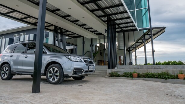 Un edificio moderno con un acceso cubierto, un automóvil estacionado al frente y una escalera que conduce a los niveles superiores.