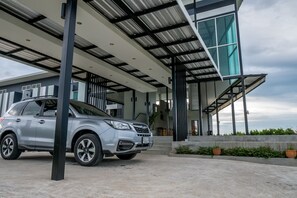 A modern building with a covered entrance, a car parked in front, and a staircase leading to the upper levels. - B3 Hotel (Nakhon Si Thammarat)