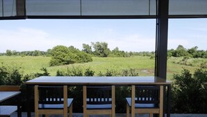 Comedor con mesa y sillas, con vista a un campo verde y árboles.