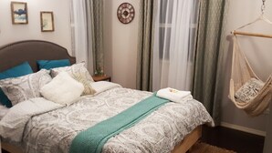A bedroom with a bed, a hanging chair, and a wall clock. - Villa Sur Colline Antigua (St. Johns)