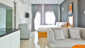 A modern hotel room with a bed, sofa, and kitchenette. - Sunflower Boutique Studio Apartment (Ho Chi Minh City)