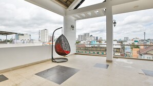 A spacious balcony with a hanging chair, a city view, and a tiled floor. - Sunflower Boutique Studio Apartment (Ho Chi Minh City)