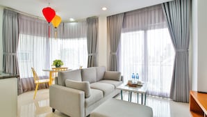 A modern living room with a sofa, ottoman, and a small table with water bottles. - Sunflower Boutique Studio Apartment (Ho Chi Minh City)