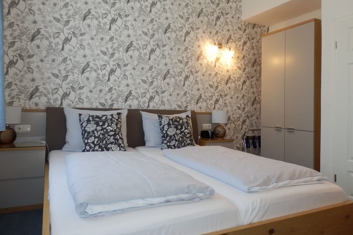 Ein Hotelzimmer mit einem großen Bett, zwei Nachttischen, einem Schrank und einer Wandleuchte.