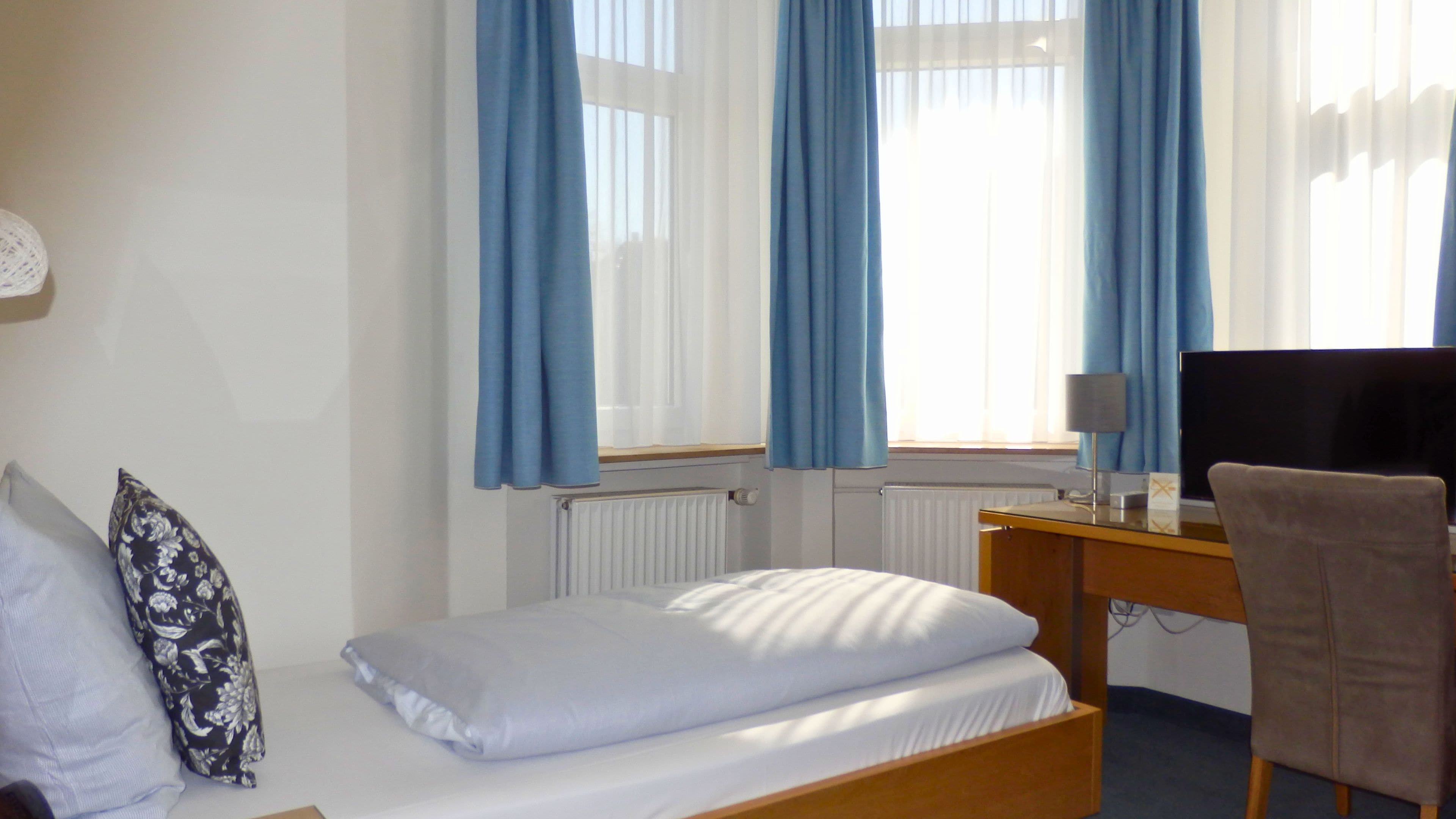 Una habitación de hotel con cama, escritorio, silla y televisión.
