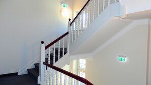 A staircase with white balusters and a wooden handrail, leading to an upper floor. - Hotel Bellevue (Hamelin)