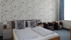 A hotel room with a large bed, two nightstands, a chair, and a window with curtains. - Hotel Bellevue (Hamelin)