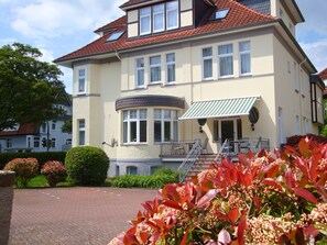 Ein zweistöckiges Gebäude mit Balkon, überdachter Eingangspartei und befestigter Auffahrt.