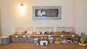 A breakfast buffet setup with labeled food items and condiments. - Hotel Bellevue (Hamelin)