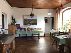 A dining area with a wooden floor, a green tablecloth-covered table, and a painting of a landscape on the wall. - Puck Landgasthof (Suderburg)
