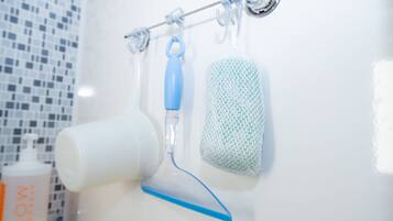 Un bagno con un lavandino bianco, uno spazzolino con manico blu e una spugna bianca appesa a un portascope.