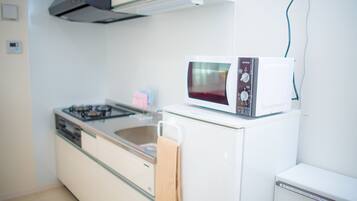 A compact kitchen with a gas stove, a microwave, and a small refrigerator.